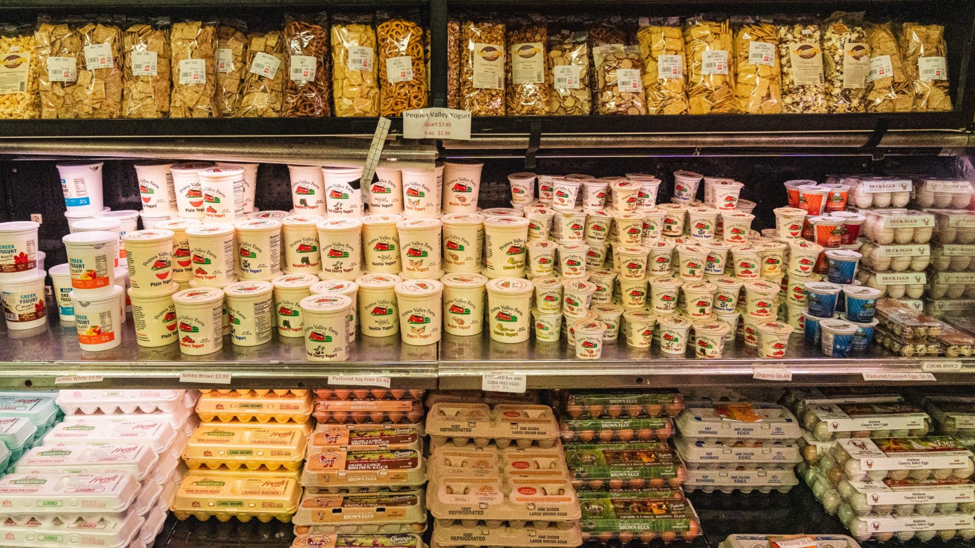 Market shelves stocked with snacks, yogurt, cheese, and farm eggs